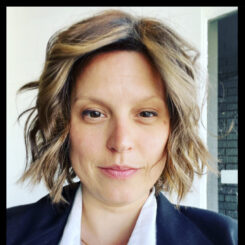 Cassandra smiles slightly at the camera while wearing a navy blue blazer and white top.