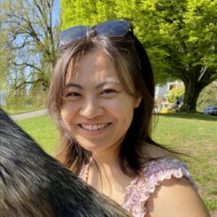 Xu Xu smiles widely at the camera with sunglasses perched atop head in an outdoor park setting.