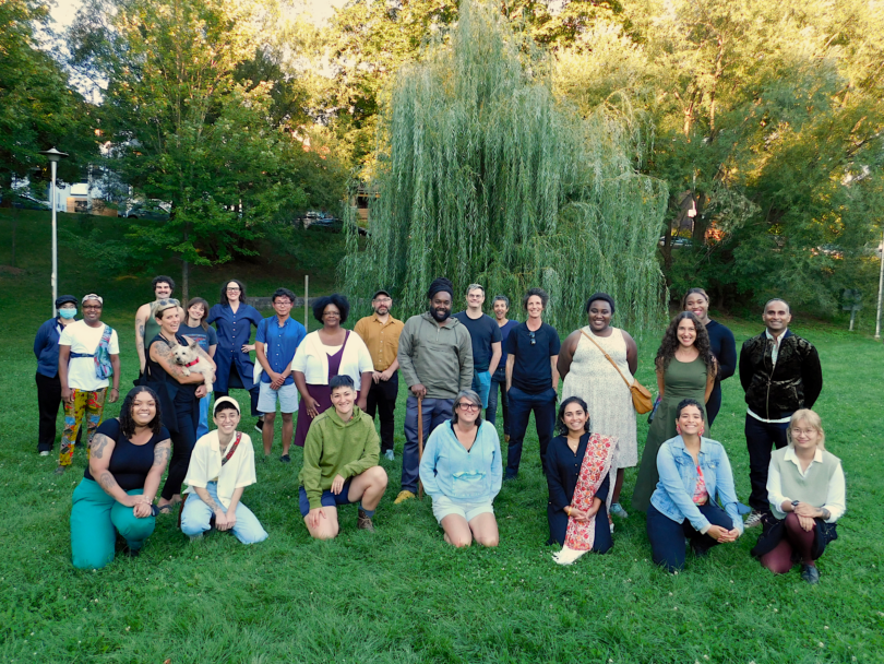 Gathered in a park, various members of the Queer and Trans Research Lab and broader SDS community face the camera, smiling. 