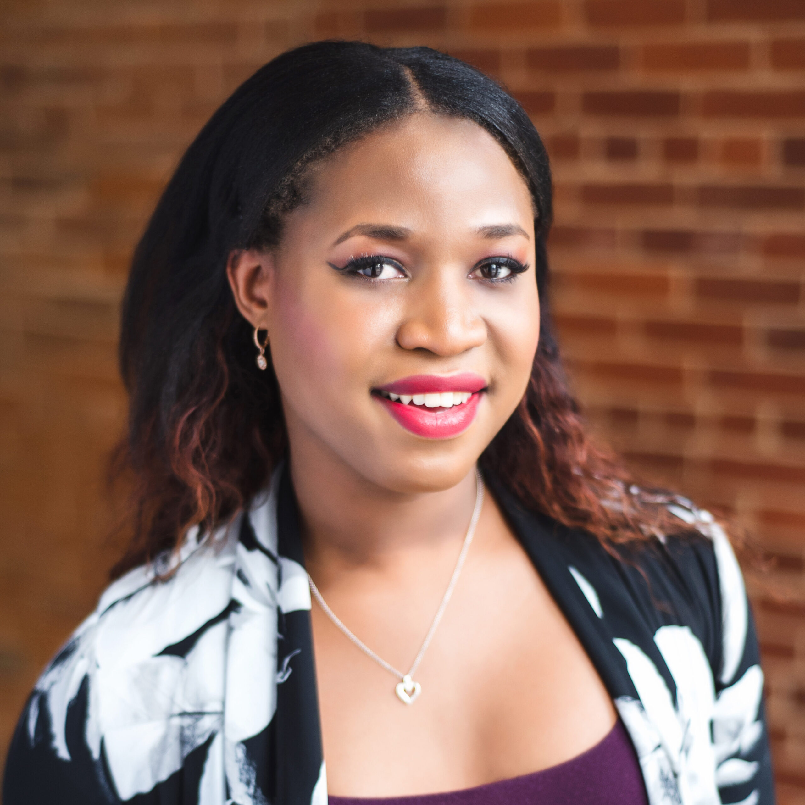 Tatiana Ferguson smiles at the camera. She wears a black and white print blazer and purple shirt.